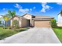 Traditional one-story home with a two-car garage and driveway, complimented by a lawn with landscaping at 15507 Caynor Ash Ln, Sun City Center, FL 33573