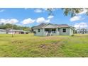 Green house with a large backyard and a covered patio with an outdoor kitchen at 12484 Green Oak Ln, Dade City, FL 33525