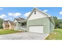 A charming home with a covered front porch and an attached two-car garage and brick paved driveway at 12484 Green Oak Ln, Dade City, FL 33525