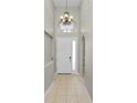 Bright foyer with tile flooring, chandelier lighting, and arched transom window above a white front door at 30816 Pumpkin Ridge Dr, Wesley Chapel, FL 33543