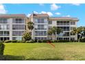 Lovely condo building featuring manicured green lawn and mature palm trees at 605 Sutton Pl # 102, Longboat Key, FL 34228