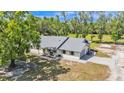 Aerial view of a charming single-story home featuring a grey roof and spacious backyard with mature trees and a long driveway at 4910 Thonotosassa Rd, Plant City, FL 33565