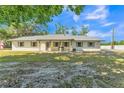Charming single-story home featuring a painted brick facade, covered porch, and a well-maintained front yard with mature trees at 4910 Thonotosassa Rd, Plant City, FL 33565