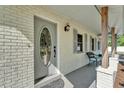Inviting front porch featuring a decorative door, gray painted brick, outdoor lighting, and seating with decorative shutters at 4910 Thonotosassa Rd, Plant City, FL 33565