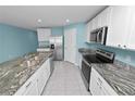 Open kitchen featuring an island, white cabinets, granite countertops, and stainless appliances at 8009 Sail Clover Ln, Zephyrhills, FL 33540