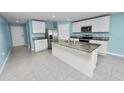 Bright kitchen featuring an island, white cabinets, stainless steel appliances, and granite countertops at 8009 Sail Clover Ln, Zephyrhills, FL 33540