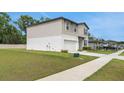 Two-story home featuring a white garage door and siding, on a large, well maintained grassy lot at 203 Lovely Ct, Plant City, FL 33566