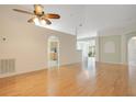 Open living room with gleaming hardwood floors, neutral paint, and an arched doorway to the kitchen at 14385 Saltby Pl, Spring Hill, FL 34609