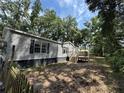 Angle view of the backyard featuring a well-maintained home with vinyl siding, complemented by a wooden deck and lush greenery at 39204 Bay Ave, Zephyrhills, FL 33540