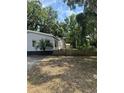 The exterior shows a yard with a quaint fence and a view of the house, complete with a deck and lush trees at 39204 Bay Ave, Zephyrhills, FL 33540