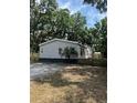 This property features a well-maintained gravel driveway leading to a cozy home with a fenced yard and lush surrounding trees at 39204 Bay Ave, Zephyrhills, FL 33540