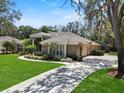 Beautiful home featuring mature trees, lush lawn and a driveway leading to an attached garage at 6007 Hammock Hill Ave, Lithia, FL 33547