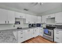Bright kitchen with white cabinets, stainless steel appliances, and granite countertops, offering ample space at 114 Windy Pl, Brandon, FL 33511