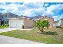 Single-story home featuring a two-car garage, green lawn, and mature palm tree at 3425 San Moise Pl, Plant City, FL 33567