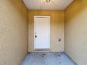 Close up of the front door with a neutral color and a textured exterior wall at 12043 Centralia Rd, Weeki Wachee, FL 34614