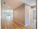 Hallway leading to the living room featuring light wood flooring, modern lighting, and neutral paint at 12053 Centralia Rd, Weeki Wachee, FL 34614