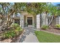 Charming home entrance with decorative pillars, a stone pathway, and verdant landscaping at 7313 Crape Myrtle Way, Sarasota, FL 34241