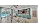 Bright living room with built-in shelving, a ceiling fan and sliding doors to an outdoor pool at 15706 Starling Water Dr, Lithia, FL 33547