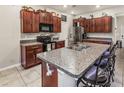 Open kitchen featuring granite countertops, dark wood cabinets, and stainless steel appliances at 10642 Lake Montauk Dr, Riverview, FL 33578