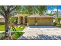 Charming home with a well-manicured lawn, mature trees, a red door, and a three-car garage at 3620 Cordgrass Dr, Valrico, FL 33596