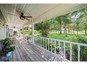 Expansive covered front porch with white railings, overlooking a lush green yard at 9912 Pine Leaf Ln, Dade City, FL 33525