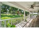 Relaxing porch with white railings, ceiling fans, and scenic views of the lush front yard at 9912 Pine Leaf Ln, Dade City, FL 33525