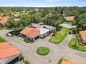 Aerial view of home highlighting tile roof, driveway, green lawn, mature trees and community pool at 107 Seville N Ct, Plant City, FL 33566