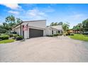 View of home showcasing driveway, gray two car garage, flag, and front landscaping at 107 Seville N Ct, Plant City, FL 33566