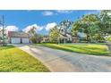 Expansive front yard showcases a well-maintained lawn, mature trees, and a detached garage, exuding suburban charm at 607 N Merrin St, Plant City, FL 33563