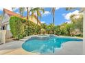 Inviting pool area with a spa, surrounded by lush greenery and a privacy fence, perfect for relaxation at 607 N Merrin St, Plant City, FL 33563