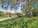 Home with manicured lawn, mature trees, and lush landscaping enhancing its curb appeal at 5903 Cachette De Riviera Ct, New Port Richey, FL 34655