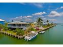 Waterfront home featuring a metal roof, white trim, boat dock and lush landscaping at 9712 Little Gasparilla Is, Boca Grande, FL 33921