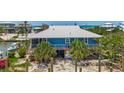 Coastal home with a metal roof and screened porch is elevated over tropical landscaping at 9712 Little Gasparilla Is, Boca Grande, FL 33921