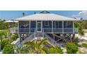 Coastal home featuring a metal roof, screened porch, white trim and lush tropical landscaping at 9712 Little Gasparilla Is, Boca Grande, FL 33921