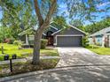 Inviting home featuring a well-maintained lawn, mature trees, and a two-car garage, perfect for Gathering living at 16804 Hawkridge Rd, Lithia, FL 33547