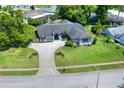 Aerial view of a single-story home with a large driveway, a lush lawn, and mature trees at 8721 Latham Ln, Hudson, FL 34667