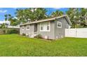 Gray single-story home showcasing a neat lawn with clean, white fence at 1603 N Park Rd, Plant City, FL 33563