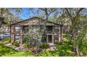 Two-story condo with mature trees, black railings, and well-maintained landscaping on a sunny day at 4022 Tumble Wood Trl # 101, Tampa, FL 33613
