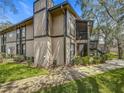 A low angle view of a two story condo with neutral paint and black trim surrounded by landscaping at 4022 Tumble Wood Trl # 101, Tampa, FL 33613