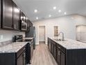Bright kitchen featuring stainless steel appliances, dark cabinets, an island and an open concept design at 35402 Coventry Fields Loop, Zephyrhills, FL 33541