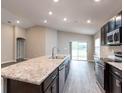 Modern kitchen featuring stainless steel appliances, dark cabinets, an island and an open concept design at 35402 Coventry Fields Loop, Zephyrhills, FL 33541