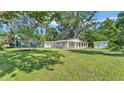 Wide shot of backyard with a spacious lawn, mature trees, trampoline, and storage shed at 4818 Huron St, Zephyrhills, FL 33541