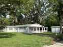 Inviting single-story home with a spacious front yard and a cozy front porch, shaded by mature trees at 4818 Huron St, Zephyrhills, FL 33541