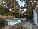 Backyard pool area with a wooden deck, complete with outdoor dining furniture and lush greenery, perfect for entertaining at 4818 Huron St, Zephyrhills, FL 33541