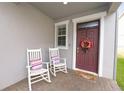 Charming front porch featuring rocking chairs and a decorative wreath on the front door at 1044 Oliveto Verdi Ct, Brandon, FL 33511