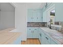 Cozy kitchen featuring tile countertops, light-blue cabinets, and modern fixtures at 275 Garden Rd, Venice, FL 34293