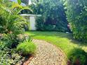 Lush backyard featuring a stone pathway, green grass, mature trees, and a shed for extra storage at 4718 Crystal Ave, Sarasota, FL 34231