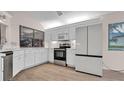Modern kitchen featuring white cabinets, stainless steel appliances, and wood-look flooring at 8050 Eacon Ct, Hudson, FL 34667