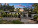 Stylish single-story home with a covered carport, black framed windows, modern landscaping, and privacy fence at sunset at 308 E Hollywood St, Tampa, FL 33604