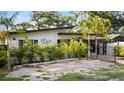 Charming single-story home featuring a modern design, black accents, and a well-manicured front yard with lush palms at 308 E Hollywood St, Tampa, FL 33604